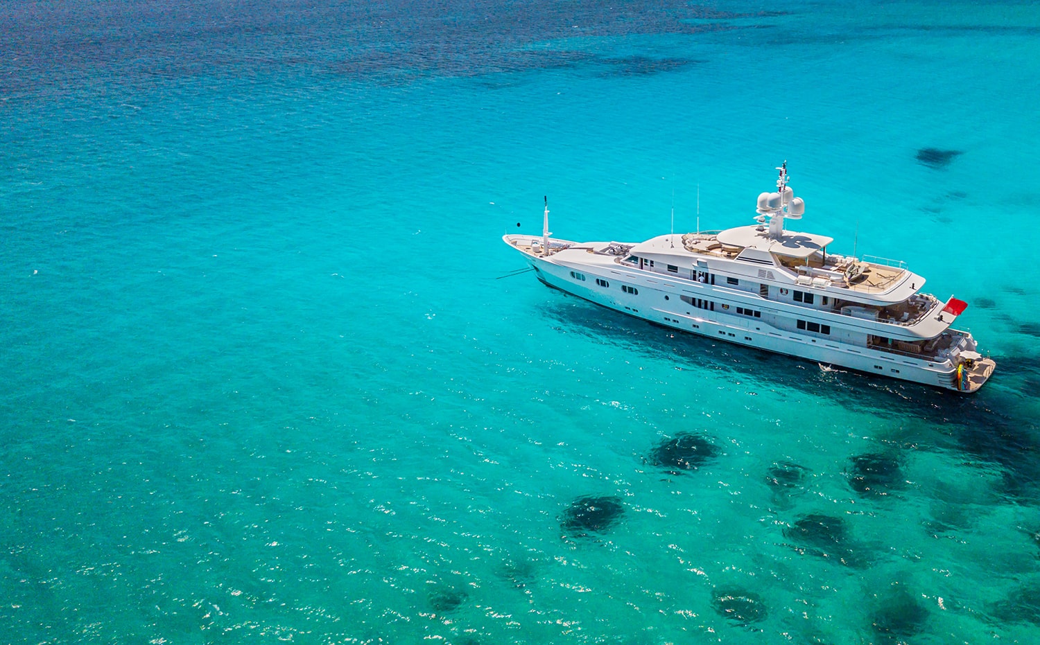 Big luxury yacht anchoring in shallow water, aerial view. Active life style, water transportation and marine sport.